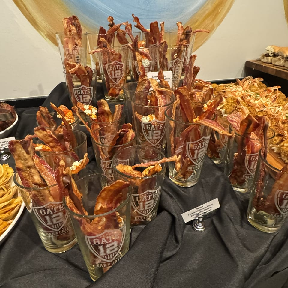 Buffet display of bacon-wrapped appetizers and crispy snacks served in branded Gate 12 Bar & Grill glasses.