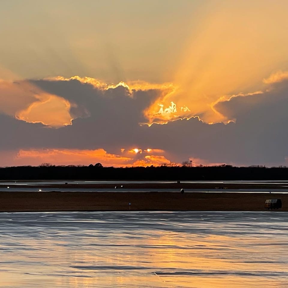 Golden sunbeams breaking through clouds over the runway after the rain.